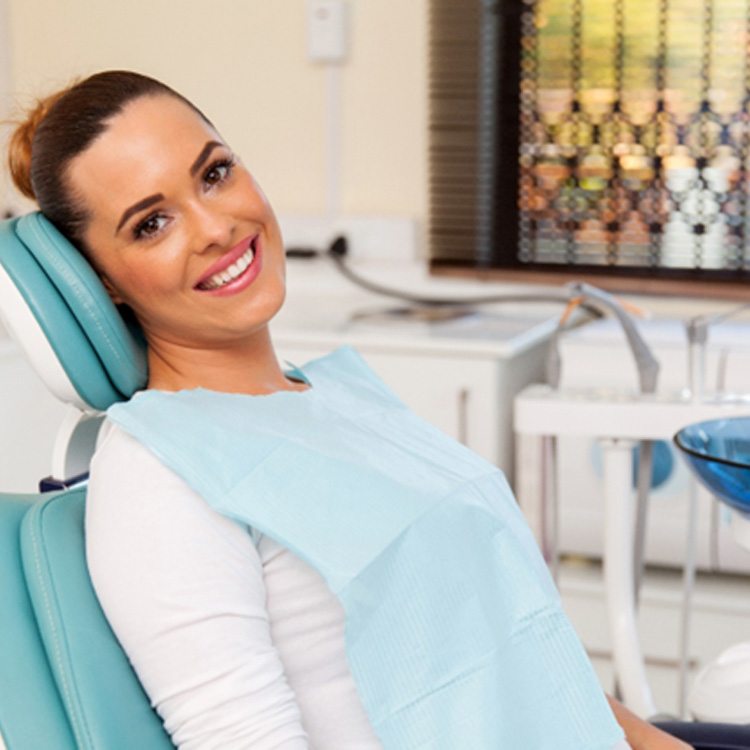 Female dental patient leaning back in chair and smiling