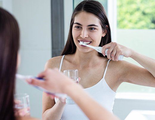 Woman brushing teeth with mechanical toothbrush