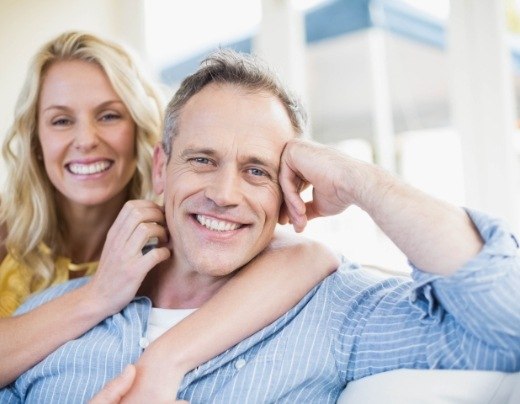 Smiling man and woman after dental implant tooth replacement