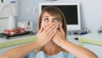 Woman in dental chair covering her mouth without sedation dentistry