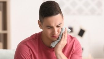 Man in need of emergency dentistry holding jaw