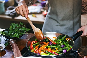 Person stir-frying colorful vegetables