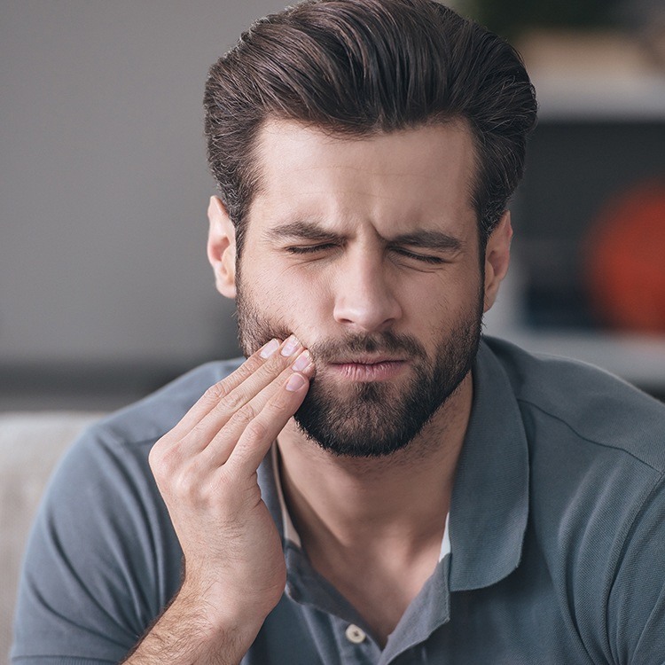 Man holding cheek before tooth extraction