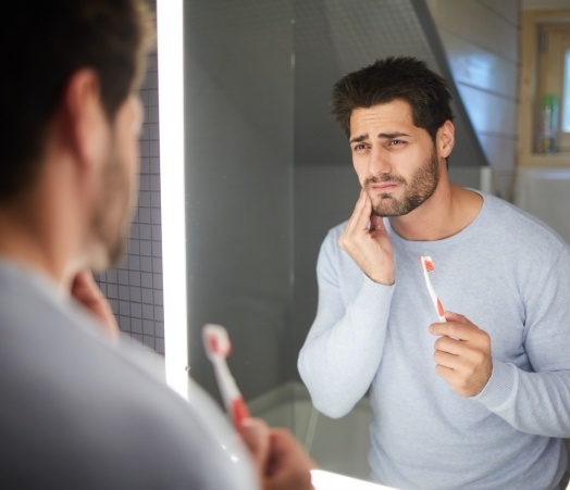 Man in need of emergency dentistry holding cheek