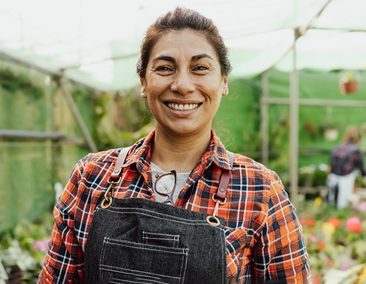 a smiling gardener standing in a greenhouse