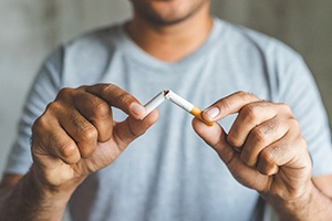 a person breaking a cigarette in half