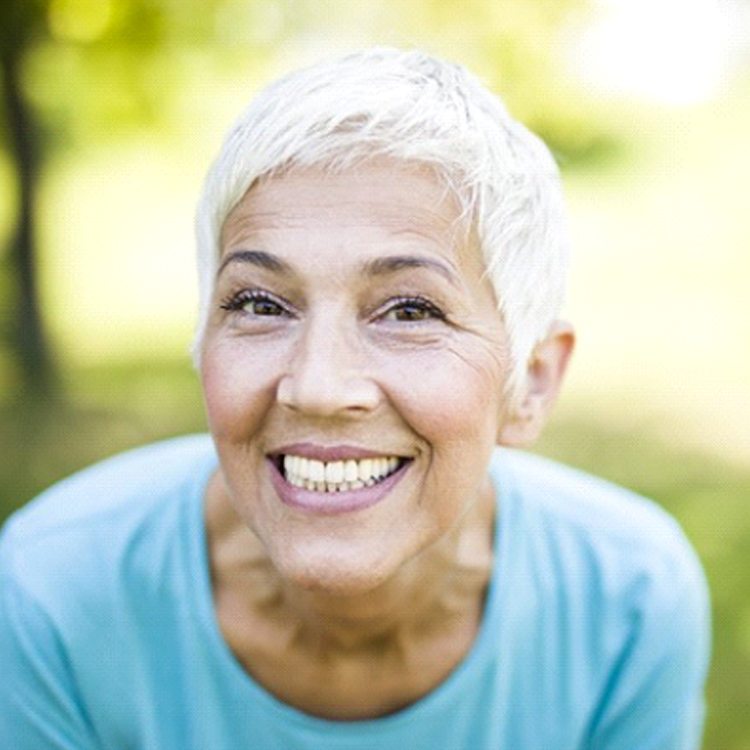 woman with implant dentures in Boerne, TX grinning from ear to ear