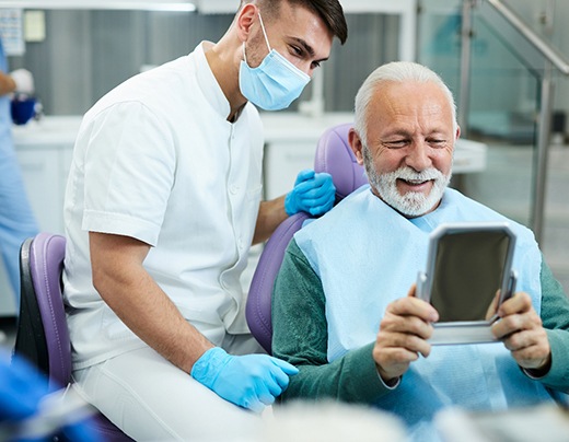 Older man smiling and learning about dental implant post-op instructions in Boerne