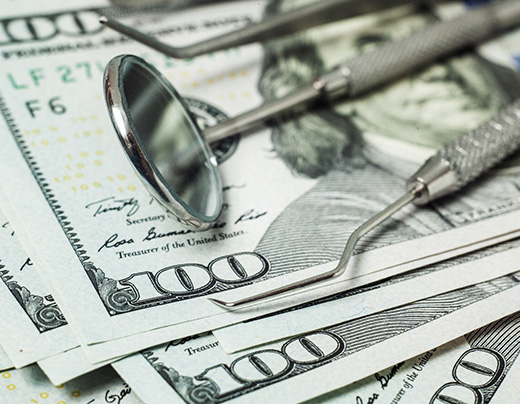 dental tools on money representing cost of dental emergencies in Boerne 