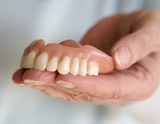 Hand holding a full set of dentures