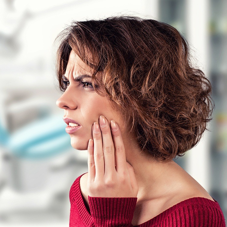 Woman in need of root canal therapy holding cheek