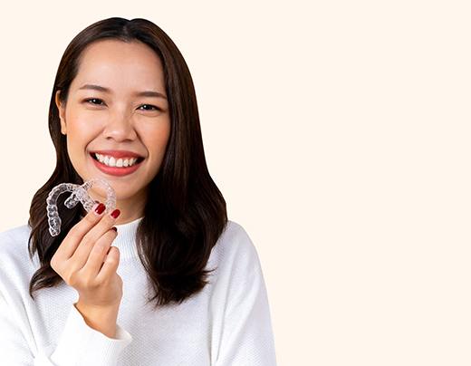 Happy woman holding two clear aligners