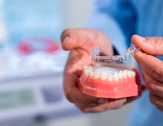 Dentist holding clear aligner and tooth model