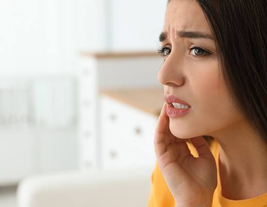 Woman in need of wisdom tooth extraction holding jaw