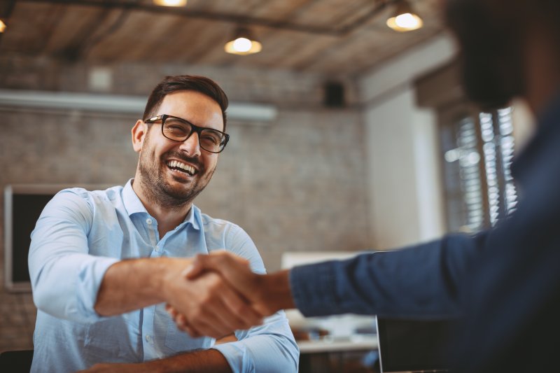 Man smiling and shaking hands at job interview