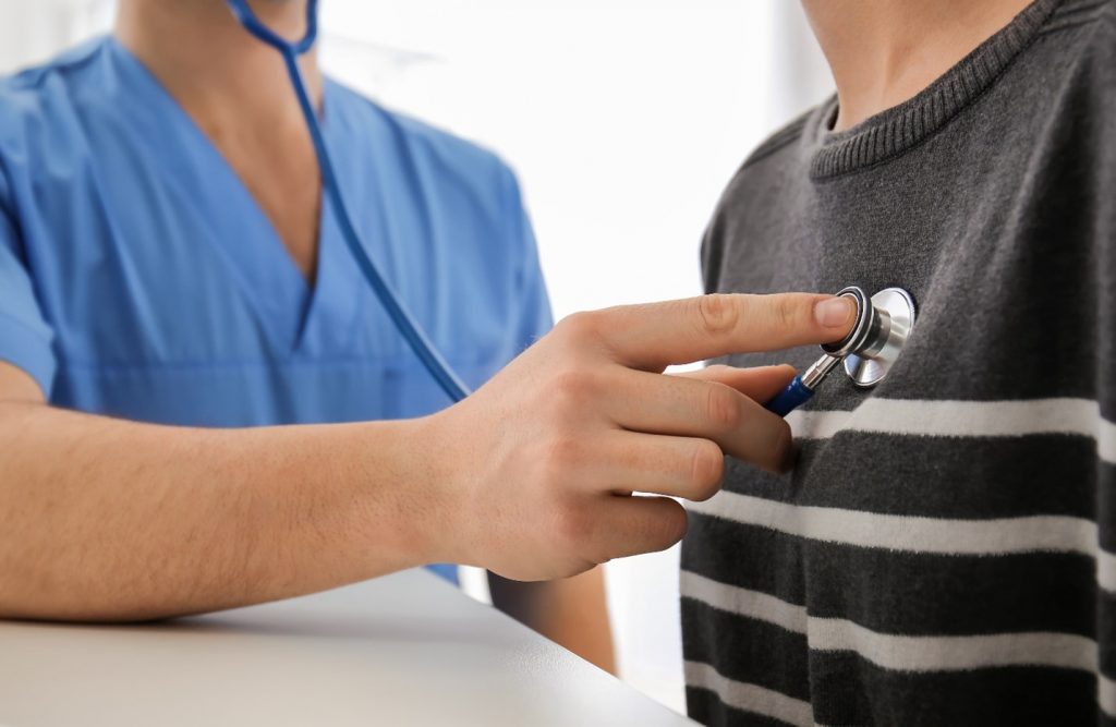 Closeup of doctor checking patient's heartbeat