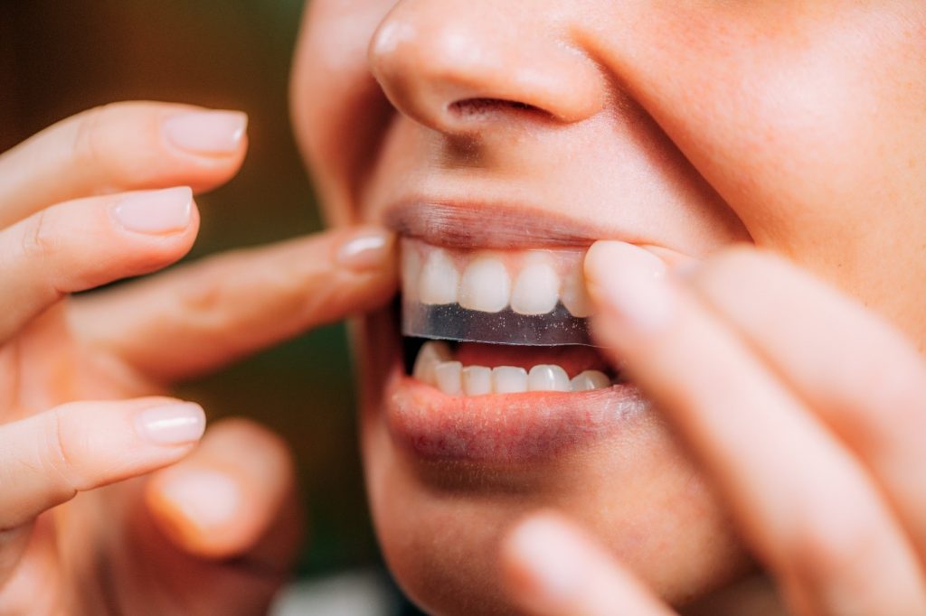 Woman applying store-bought teeth whitening strip