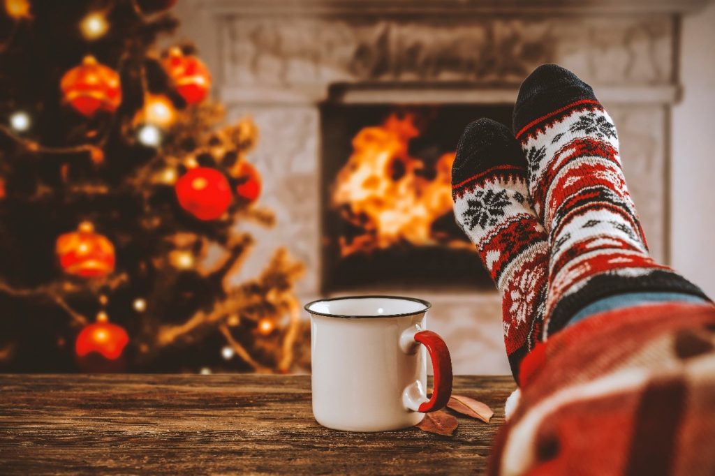 Person relaxing by fireplace in festive socks