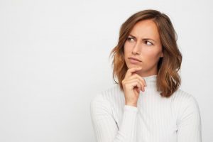 young woman thinking against white background 