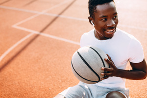 Basketball player on court holding ball and smiling 