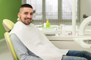 Male dental patient sitting in chair and smiling