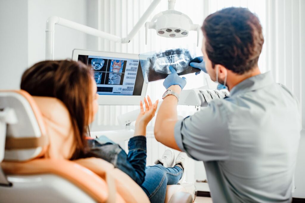 A dentist showing a patient her infected tooth on an X-ray image.